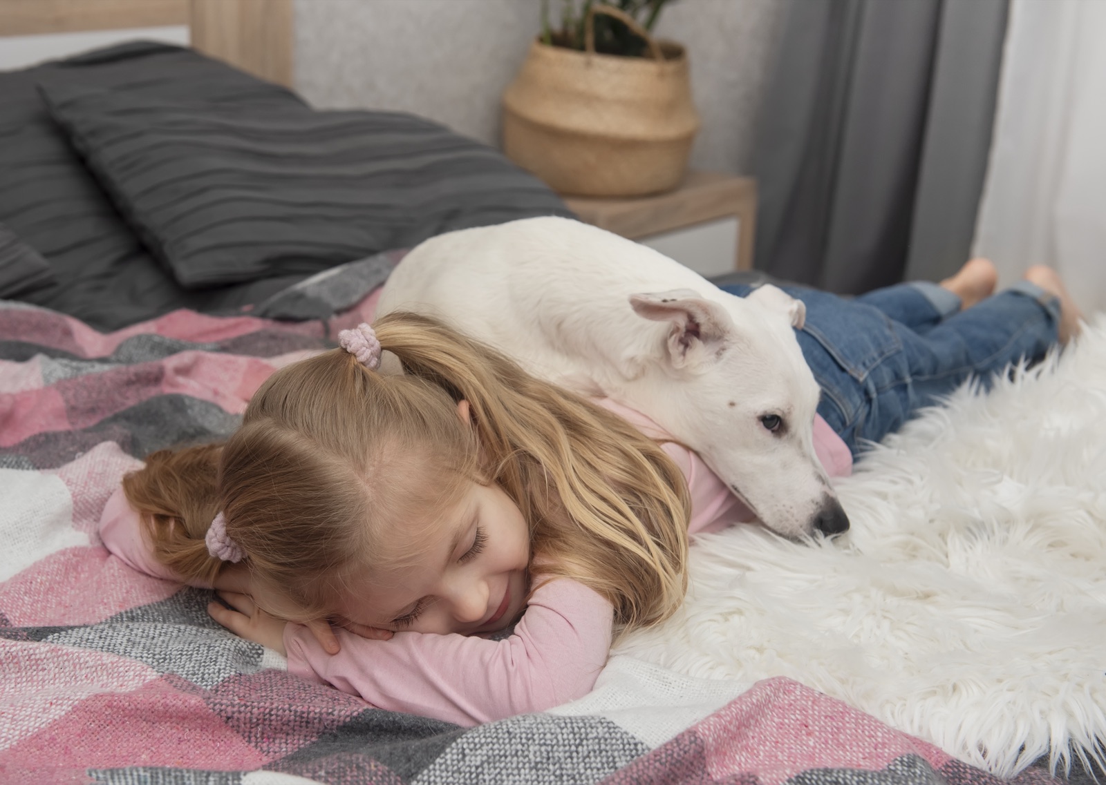 A dog lying across a resting girl's back, applying gentle steady pressure